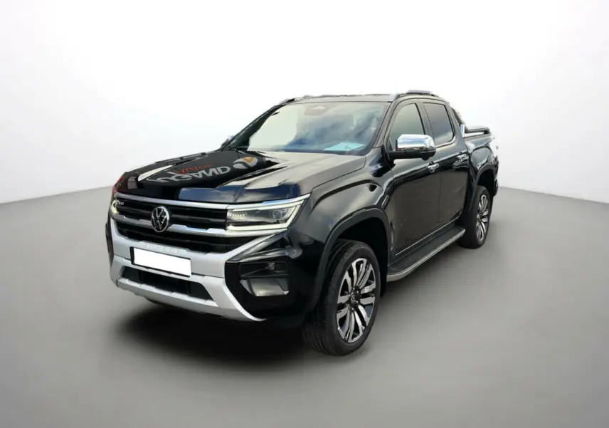 Volkswagen Amarok V6 noir en 3/4 avant droit, avec jantes alu 21 pouces et barres de toit visibles.
