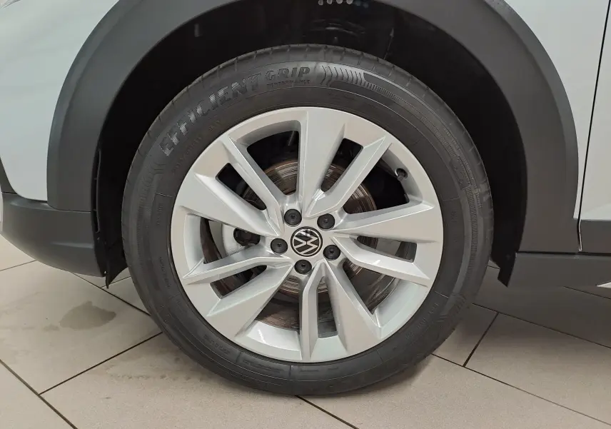 Gros plan sur la roue avant droite du Volkswagen Taigo 2025 en peinture métallisée Reflet d'argent avec jante alliage à 5 doubles branches.
