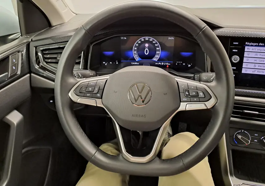 Vue intérieure centrée sur le volant multifonction du Volkswagen Taigo 2025, avec tableau de bord numérique et commandes intégrées.