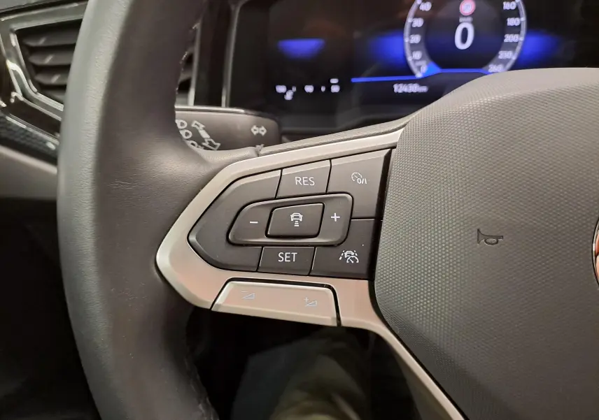 Gros plan sur les commandes au volant côté gauche du Volkswagen Taigo 2025, avec finition noire et argentée.