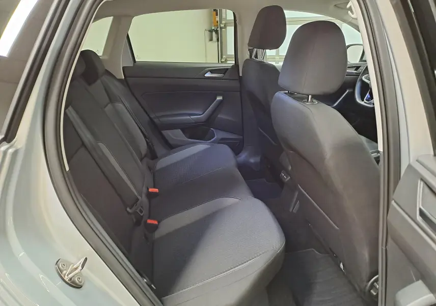 Vue intérieure côté gauche du Volkswagen Taigo 2025, montrant les sièges arrière en tissu noir et la porte ouverte couleur Reflet d'argent.
