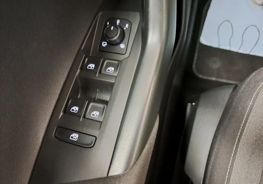 Gros plan sur les commandes de lève-vitres et rétroviseurs côté gauche du Volkswagen Taigo 2025 en intérieur noir.