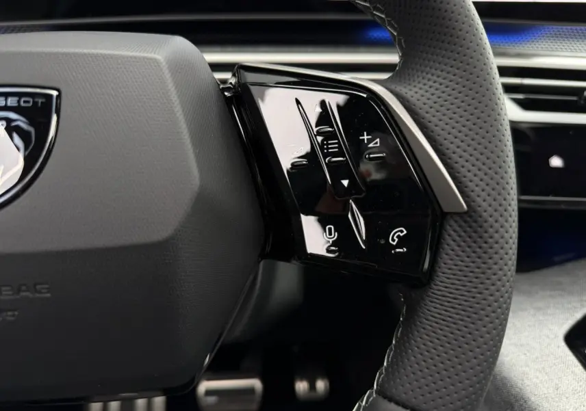 Gros plan sur les commandes à droite du volant perforé du Peugeot 3008 Hybrid GT, intérieur noir élégant.