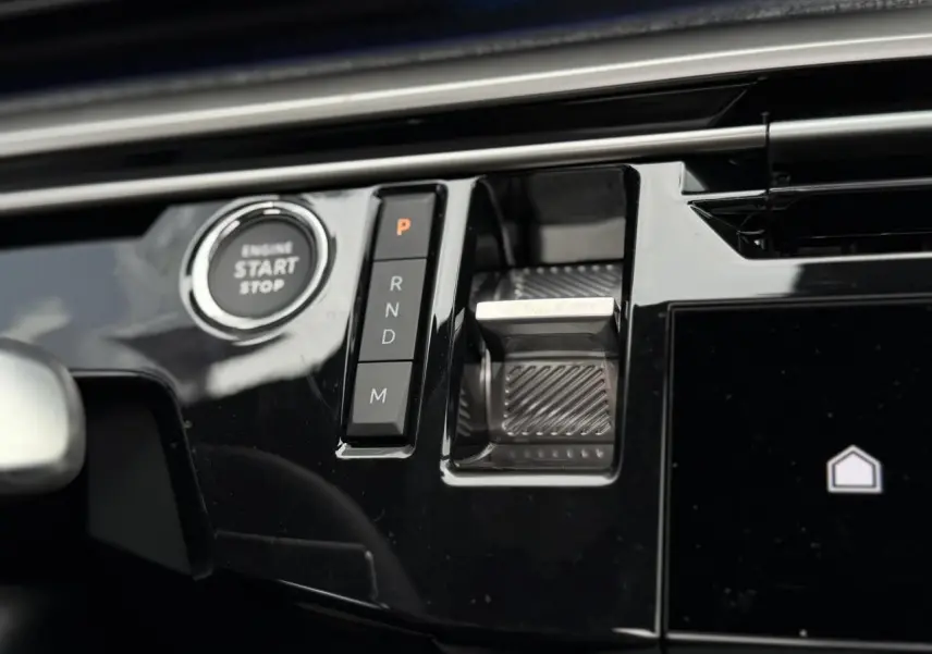 Gros plan sur la console centrale noire brillante du Peugeot 3008 Hybrid avec bouton start/stop et commandes de boîte automatique.
