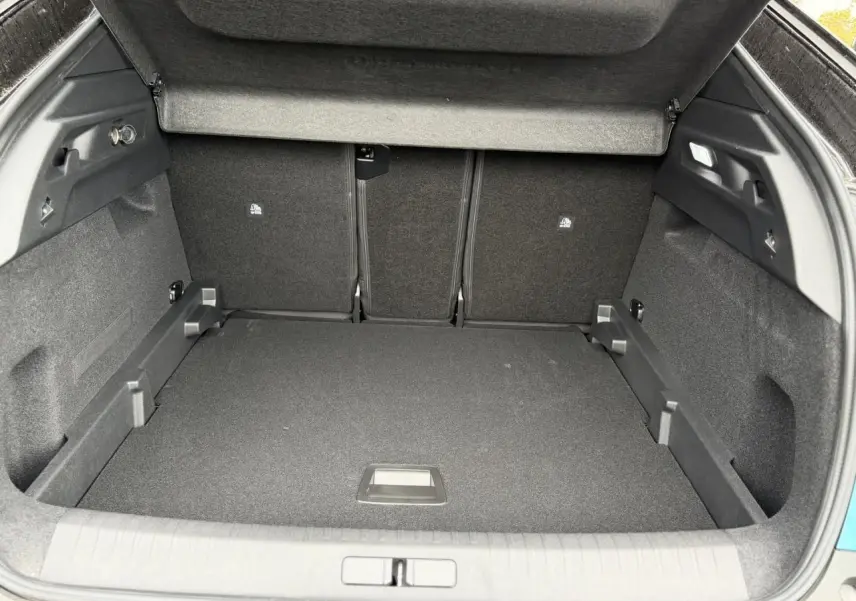Coffre ouvert vu de l'arrière d'un Peugeot 3008 Hybrid bleu Obsession avec intérieur noir et cache-bagages relevé.