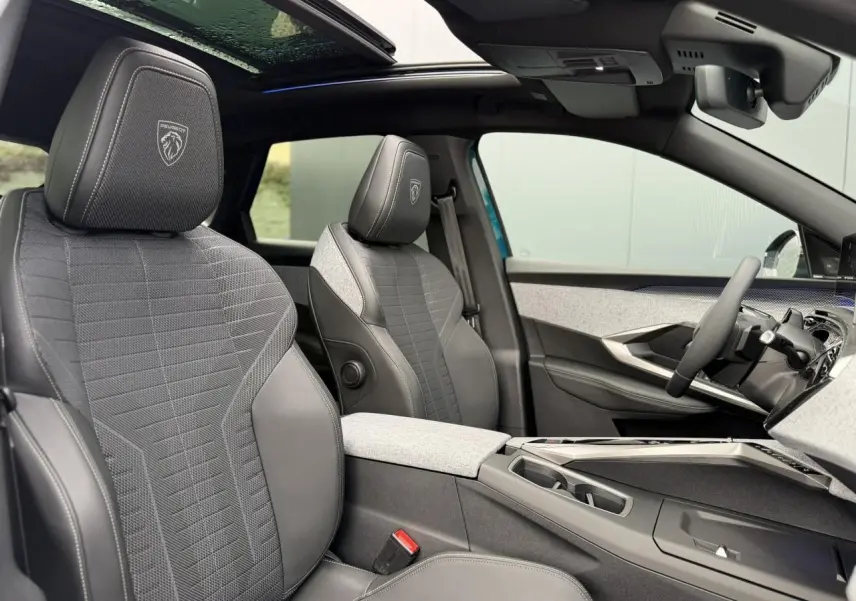 Vue intérieure côté droit du Peugeot 3008 Hybrid GT 2026, sièges tissu gris avec surpiqûres et toit ouvrant panoramique.