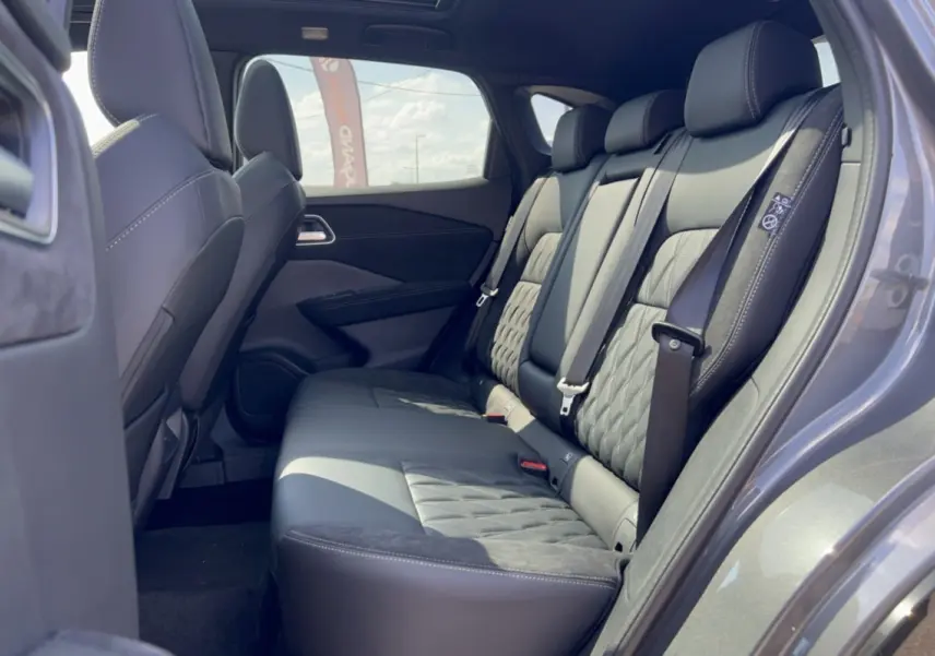 Vue latérale droite de l’intérieur arrière du Nissan Qashqai E-POWER 205 Tekna Plus avec sellerie cuir noire et détails matelassés.