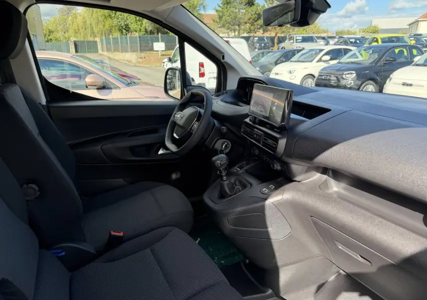 Intérieur du Peugeot Partner 2026 vu côté conducteur, montrant sièges noirs et tableau de bord avec écran tactile.