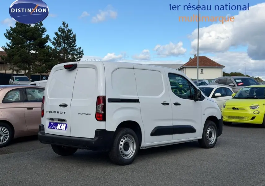 Vue 3/4 arrière droite du Peugeot Partner blanc Icy avec porte latérale coulissante, sur parking extérieur.
