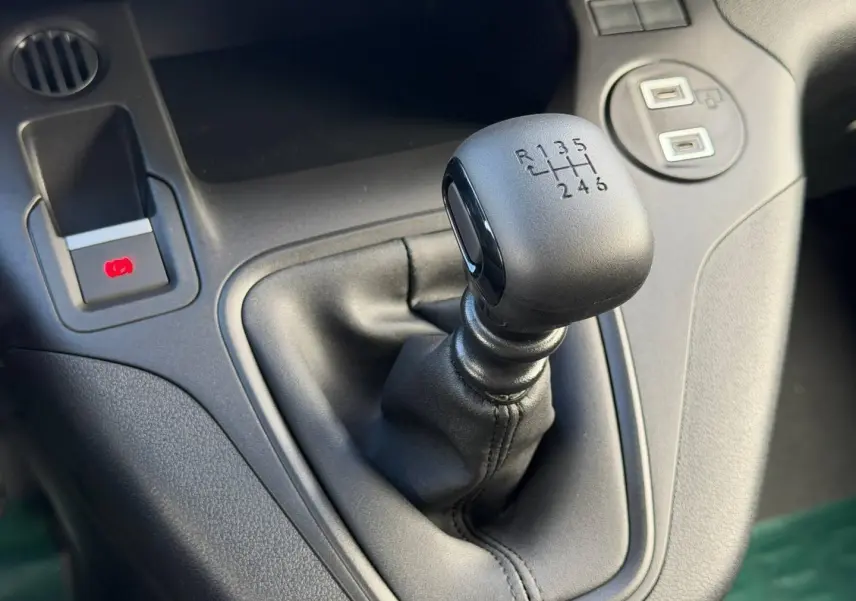 Gros plan sur le levier de vitesses manuel noir du Peugeot Partner M Diesel 100ch PACK CONFORT, intérieur gris.