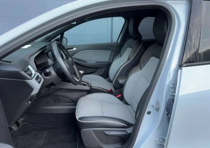 Vue intérieure côté conducteur de la Renault Clio gris rafale 2025 avec sièges bi-matière et volant cuir.