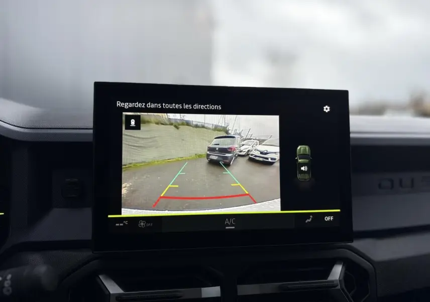 Écran tactile du Dacia Duster blanc Glacier montrant la caméra de recul avec vue arrière et lignes de guidage colorées.