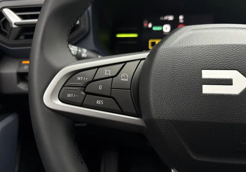Gros plan sur le volant noir du Dacia Duster 2025, montrant les commandes de régulateur de vitesse côté gauche.