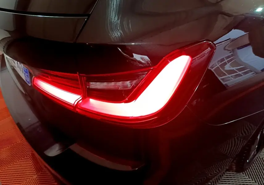 Feu arrière droit allumé d'une BMW Série 3 noire 318i M Sport, vue rapprochée du coin arrière du véhicule.