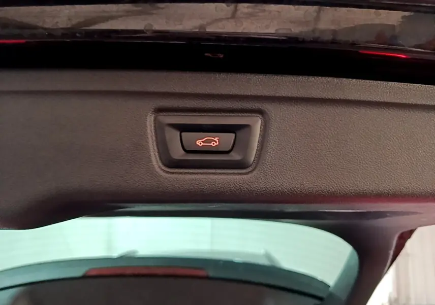 Bouton de fermeture électrique du coffre sur la partie intérieure du hayon d'une BMW Série 3 noire.