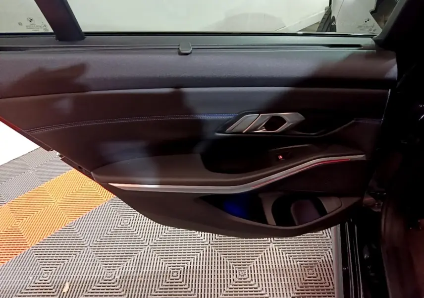 Porte intérieure côté gauche noire de BMW Série 3 318i M Sport 2022 avec éclairage d'ambiance rouge fin et poignée alu.