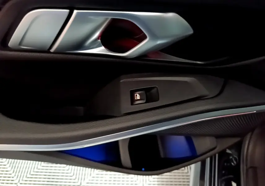 Détail de la poignée intérieure et commande de verrouillage sur la porte côté gauche d'une BMW Série 3 noire.