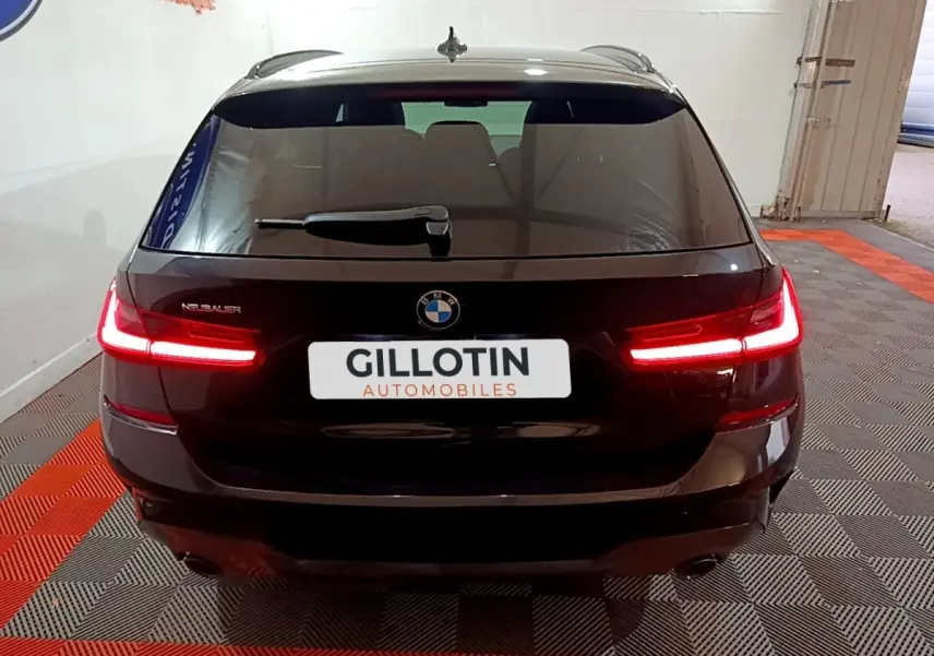 Vue arrière d'une BMW Série 3 318i noire avec feux LED allumés dans un showroom intérieur.