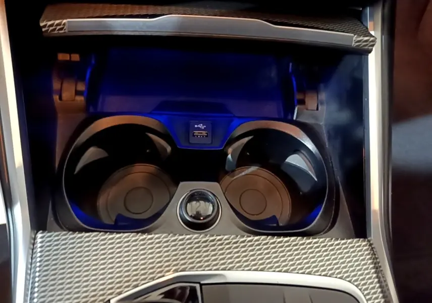 Gros plan sur la console centrale noire de la BMW Série 3 318i M Sport 2022 avec porte-gobelets et port USB.