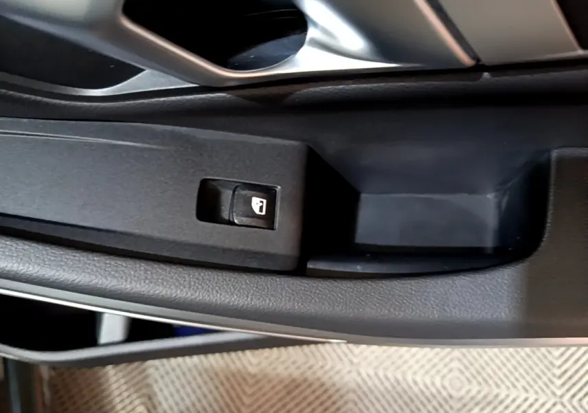 Gros plan sur le bouton de verrouillage des portes côté conducteur dans l'intérieur noir de la BMW Série 3 318i M Sport 2022.