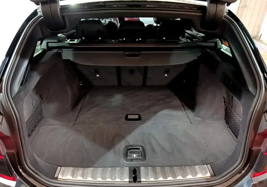 Coffre ouvert d'une BMW Série 3 noire, vue arrière montrant un espace de chargement spacieux et bien fini.