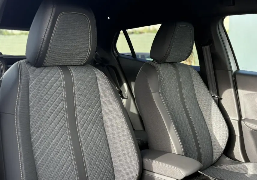 Gros plan sur les sièges avant gris et noirs du Peugeot 2008 Hybrid 145 e-DSC6 Allure, intérieur sobre et moderne.