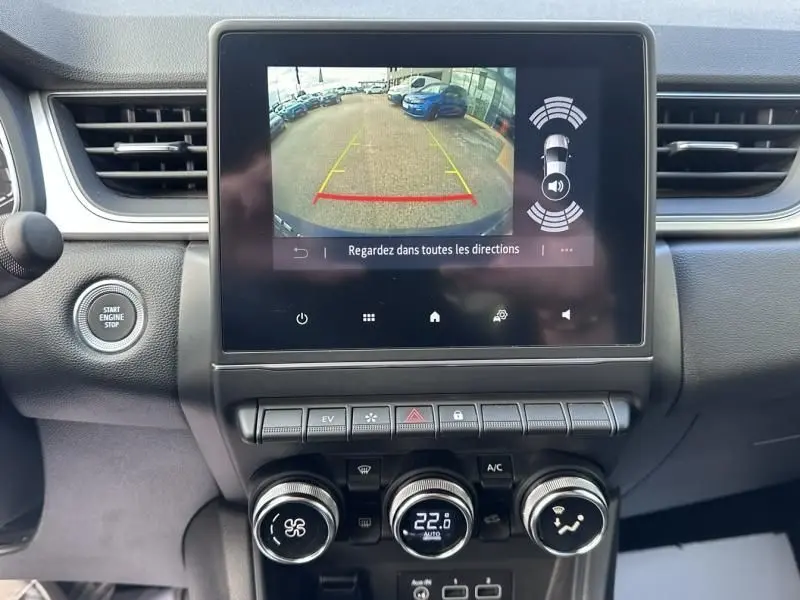 Vue intérieure du tableau de bord du Renault Captur bleu métal 2022, avec écran de caméra de recul et commandes climatisation.
