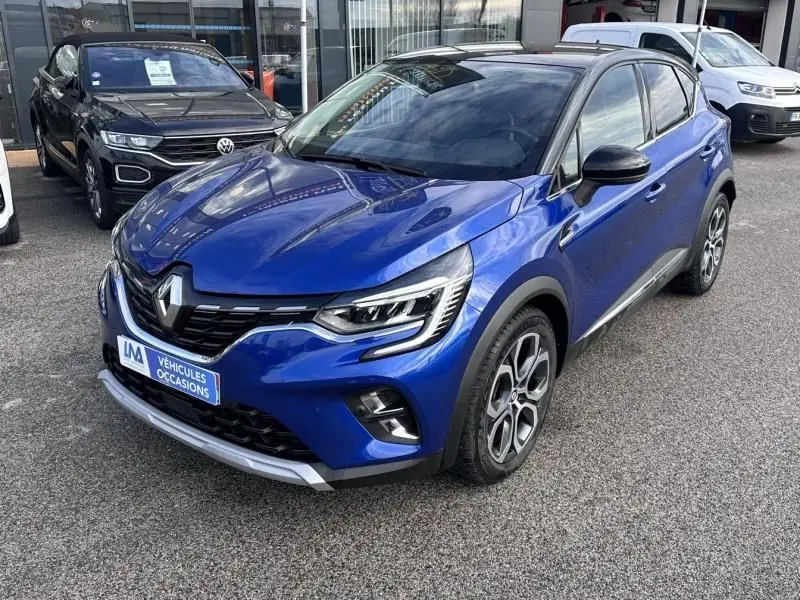 Renault Captur 1.6 E-Tech Hybride 145 Intense bleu métal, vue 3/4 avant droit avec jantes distinctives et toit noir.
