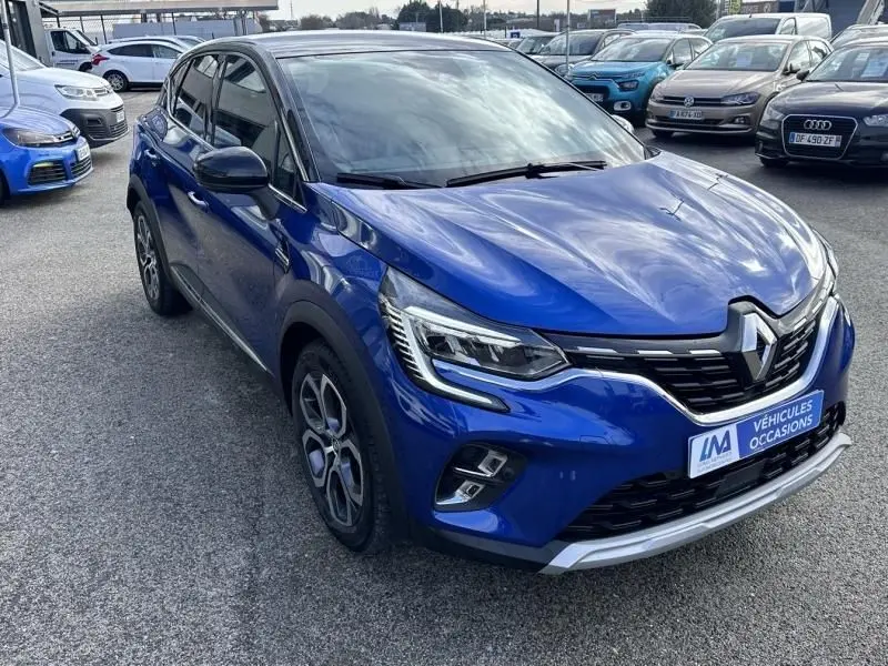 Vue 3/4 avant d'un Renault Captur bleu métal 2022 avec calandre noire et signature lumineuse LED distinctive.