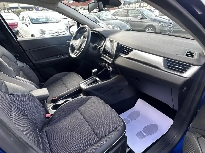 Vue intérieure côté conducteur du Renault Captur bleu métal 2022, avec tableau de bord moderne et boîte automatique.