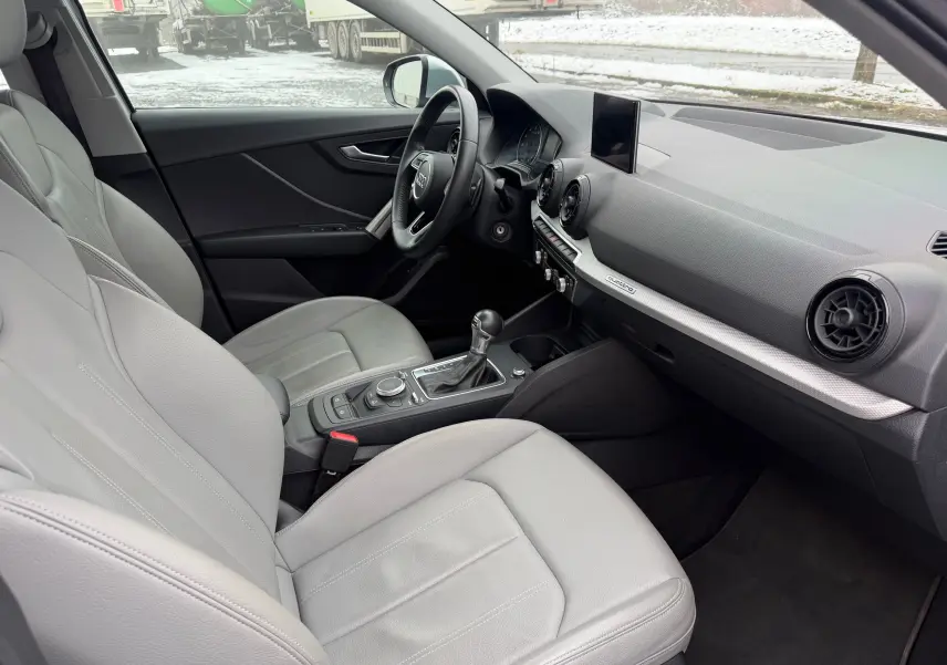 Vue intérieure côté conducteur de l'Audi Q2 2017 avec sellerie gris clair en similicuir et tableau de bord moderne.