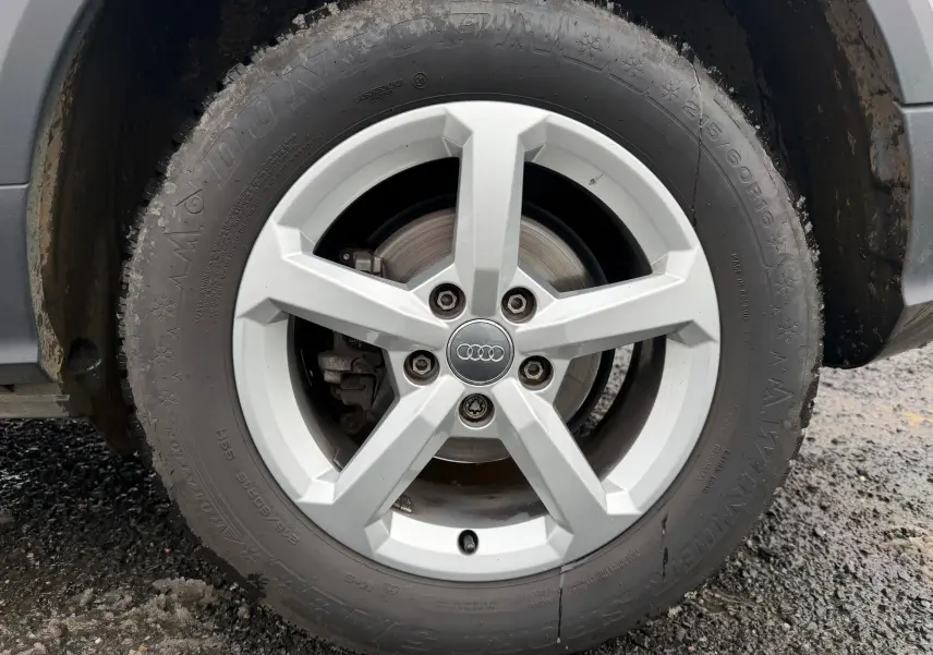 Gros plan sur la roue avant droite d’un Audi Q2 gris aluminium, avec jante alliage 5 branches et logo Audi central.