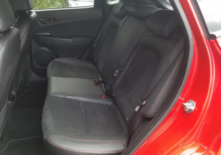 Vue intérieure côté arrière droit du Hyundai Kona rouge 2023, montrant les sièges arrière en Alcantara noir avec surpiqûres rouges.