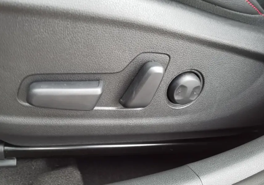 Gros plan sur les commandes électriques de réglage du siège conducteur du Hyundai Kona 2023 finition N Line rouge.