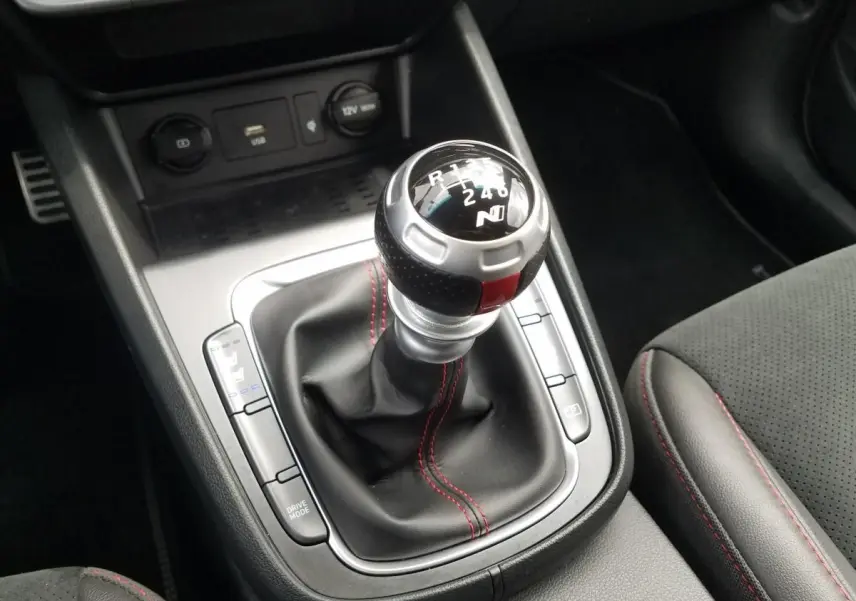 Gros plan sur le levier de vitesses manuel noir avec surpiqûres rouges dans l’habitacle du Hyundai Kona rouge N Line.