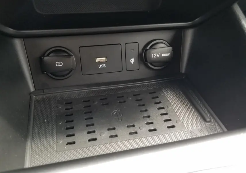 Vue rapprochée de la console centrale du Hyundai Kona rouge 2023, montrant les prises USB, 12V et chargeur sans fil.