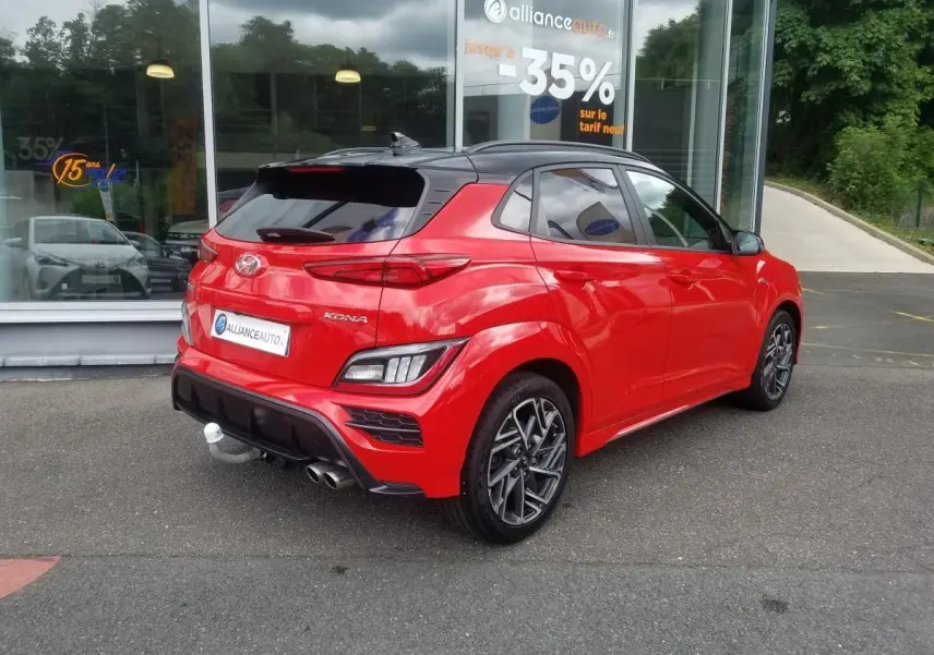 Vue 3/4 arrière droite d'un Hyundai Kona rouge avec toit noir et jantes alliage bi-ton 18 pouces N Line.