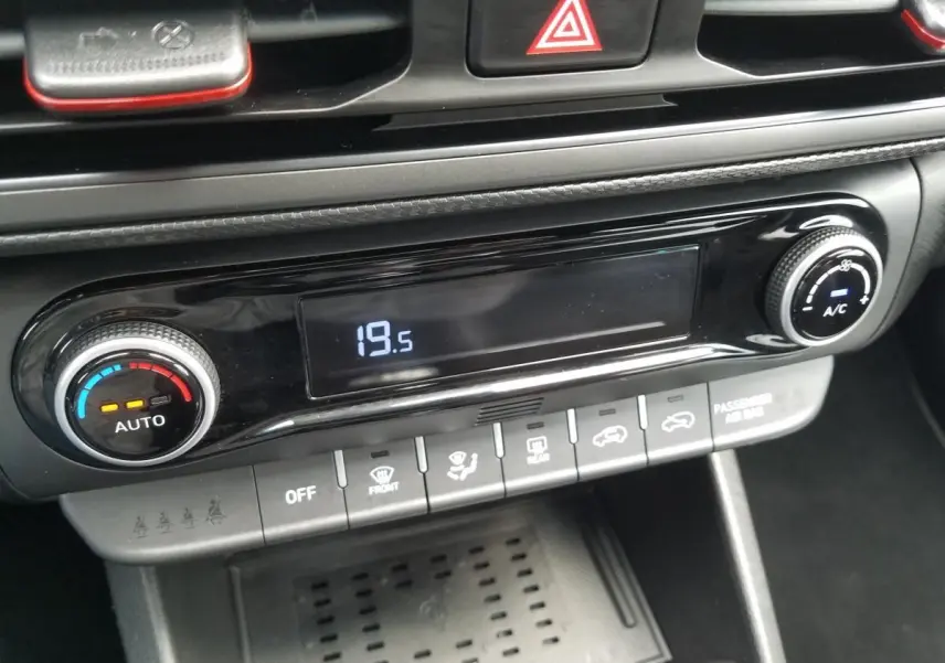 Gros plan sur la console centrale du Hyundai Kona rouge 2023, affichant la climatisation automatique à 19,5°C.