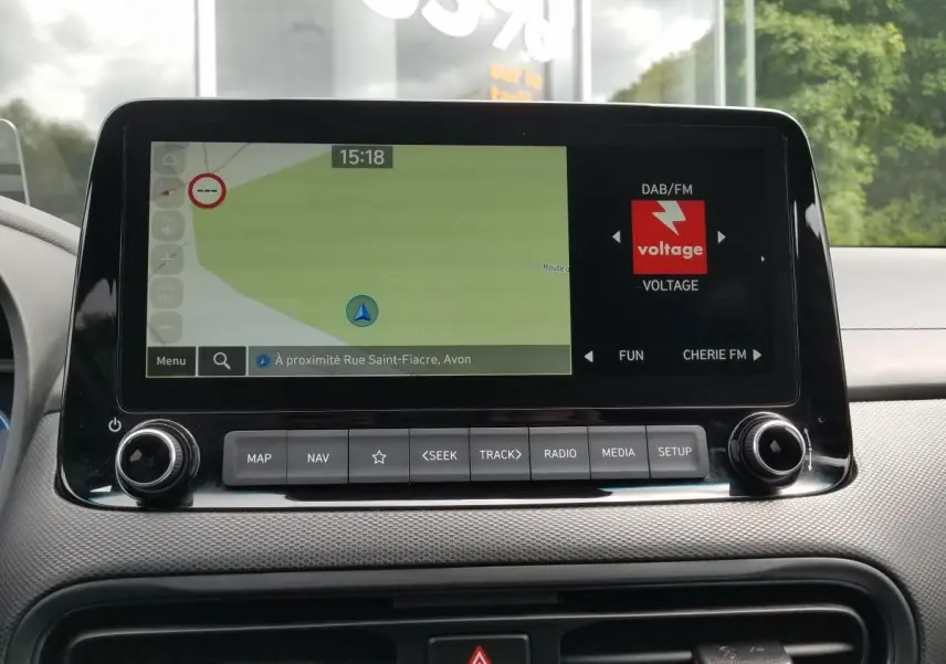 Écran central tactile du Hyundai Kona 2023 affichant la navigation et la radio, vue intérieure frontale.