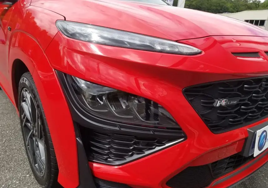 Gros plan sur l'avant droit rouge vif du Hyundai Kona N Line 2023 avec phares bi-LED et calandre noire distinctive.