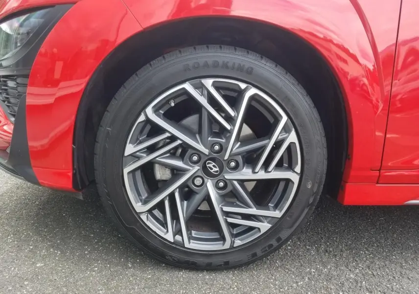 Gros plan sur la jante alliage bi-ton 18'' du côté avant gauche d’un Hyundai Kona rouge 2023.