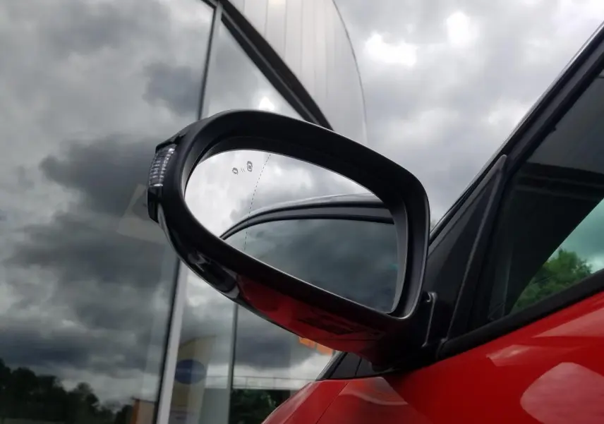 Rétroviseur extérieur droit noir contrasté du Hyundai Kona rouge, avec vitre arrière surteintée visible en arrière-plan.
