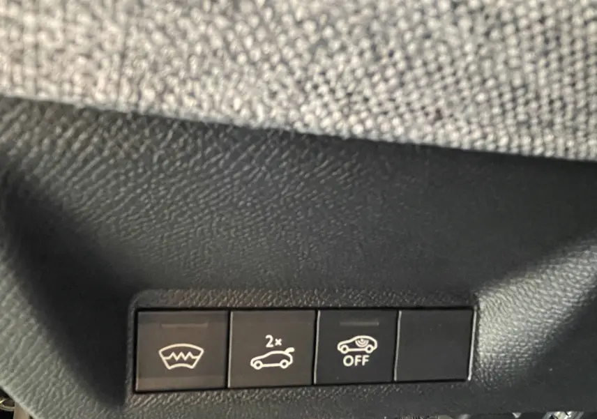 Gros plan sur les boutons de commande intérieurs noirs du Peugeot 3008 Hybrid 145, avec symbole pare-brise chauffant et ouverture coffre.