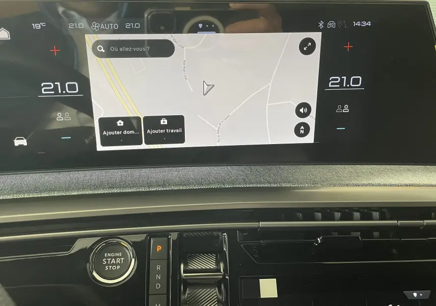 Vue rapprochée de l’écran tactile central du Peugeot 3008 hybride noir 2026 avec navigation et commandes climatisation affichées.