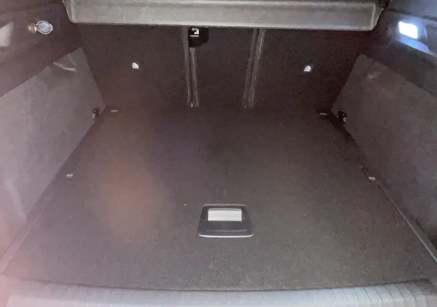 Coffre spacieux et vide du Peugeot 3008 Hybrid 145 noir, vue intérieure depuis l'ouverture arrière.