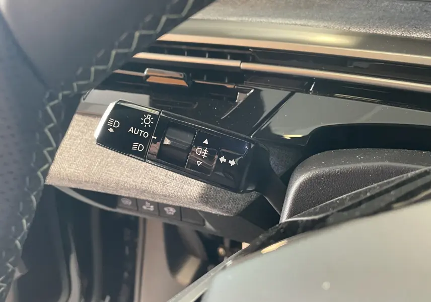 Gros plan sur la commande des feux et clignotants à gauche du volant dans l’habitacle du Peugeot 3008 noir hybride 2026.