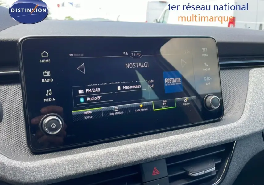 Écran tactile central du tableau de bord de la Skoda Scala blanc glacier, affichant la radio Nostalgie en FM/DAB.