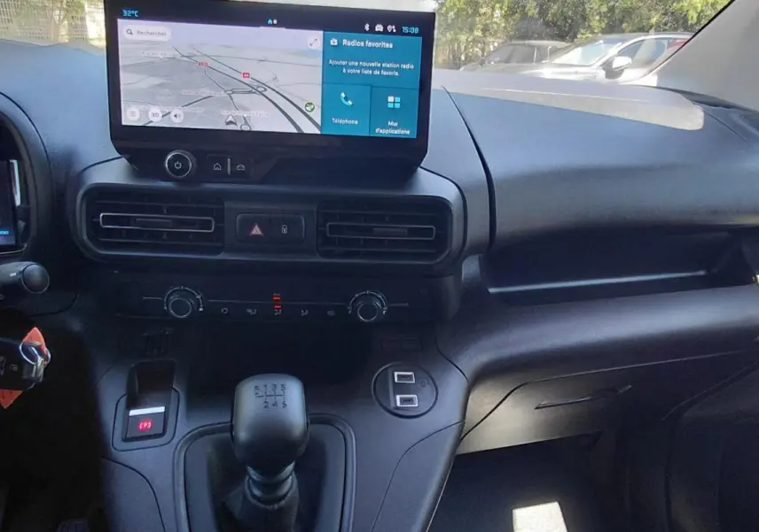 Vue intérieure de face du tableau de bord noir du Citroën Berlingo 2025 avec écran tactile et levier de vitesse manuel.