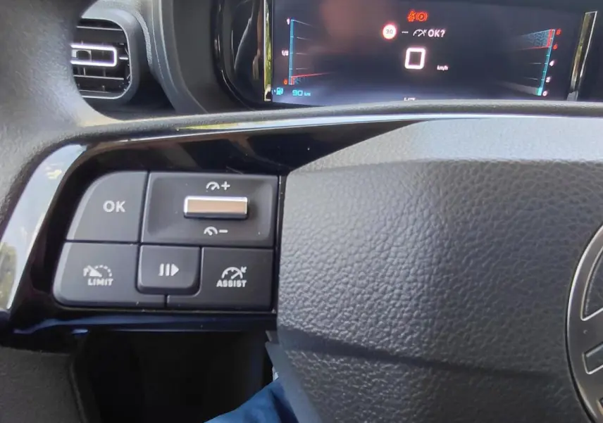 Gros plan sur le volant multifonctions noir du Citroën Berlingo 2025, avec commandes de limiteur et assistance.