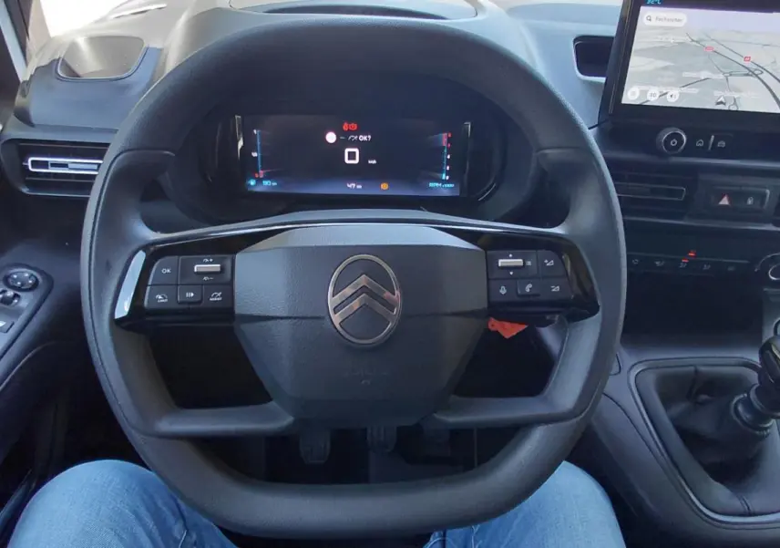 Vue intérieure centrée sur le volant multifonctions et le tableau de bord numérique du Citroën Berlingo blanc 2025.